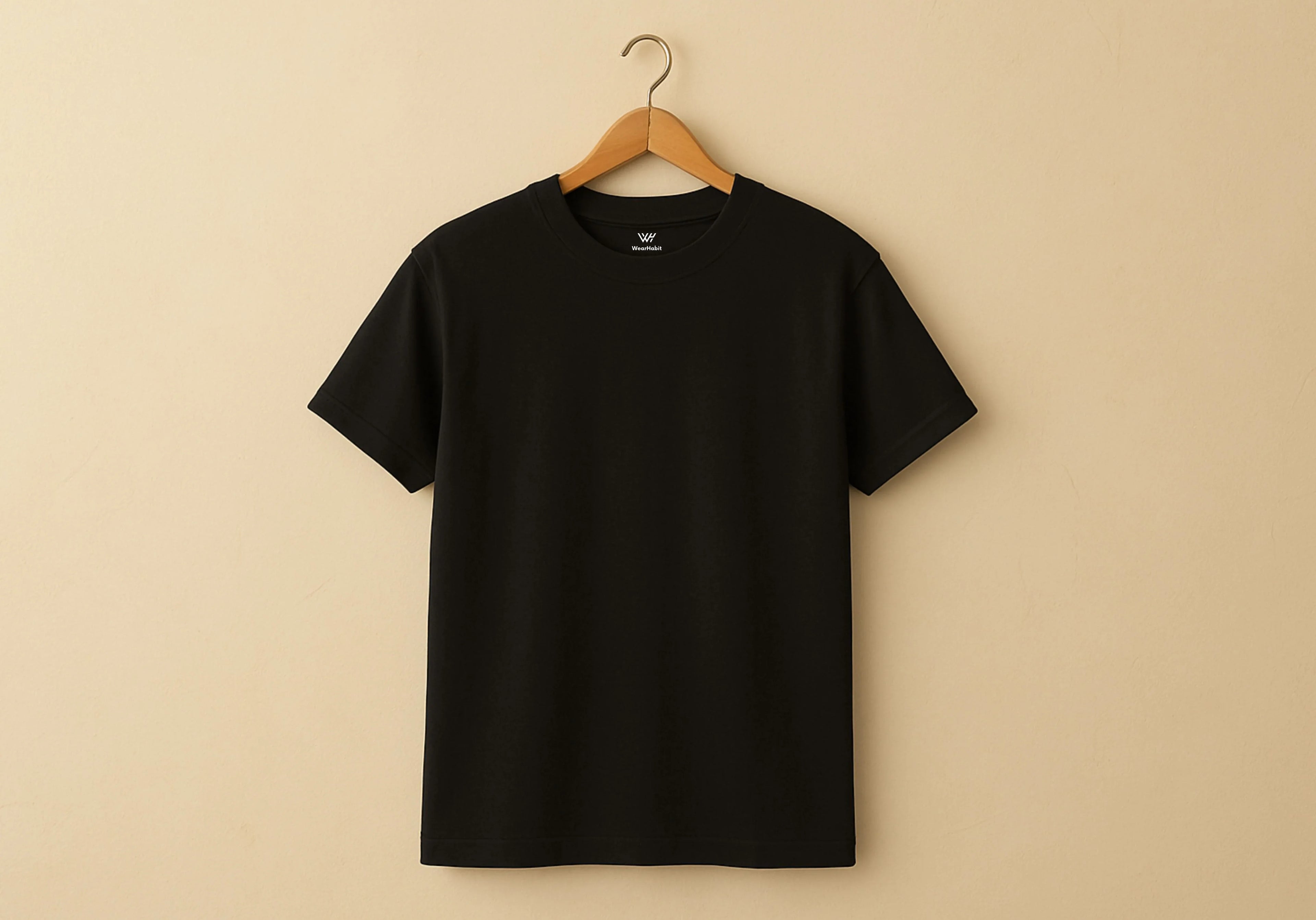 Black t-shirt on a wooden hanger against a beige background