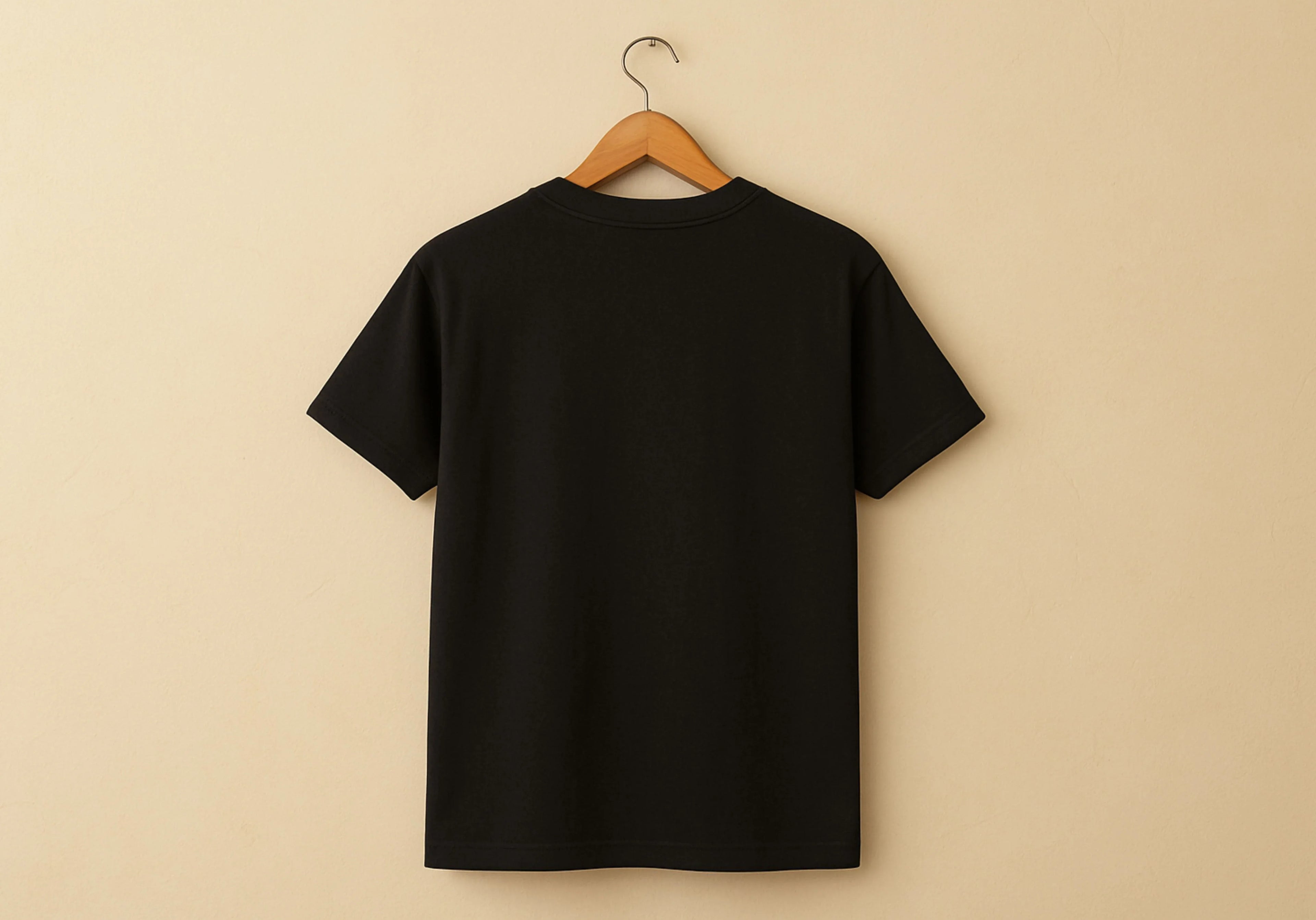 Black t-shirt on a hanger against a beige background