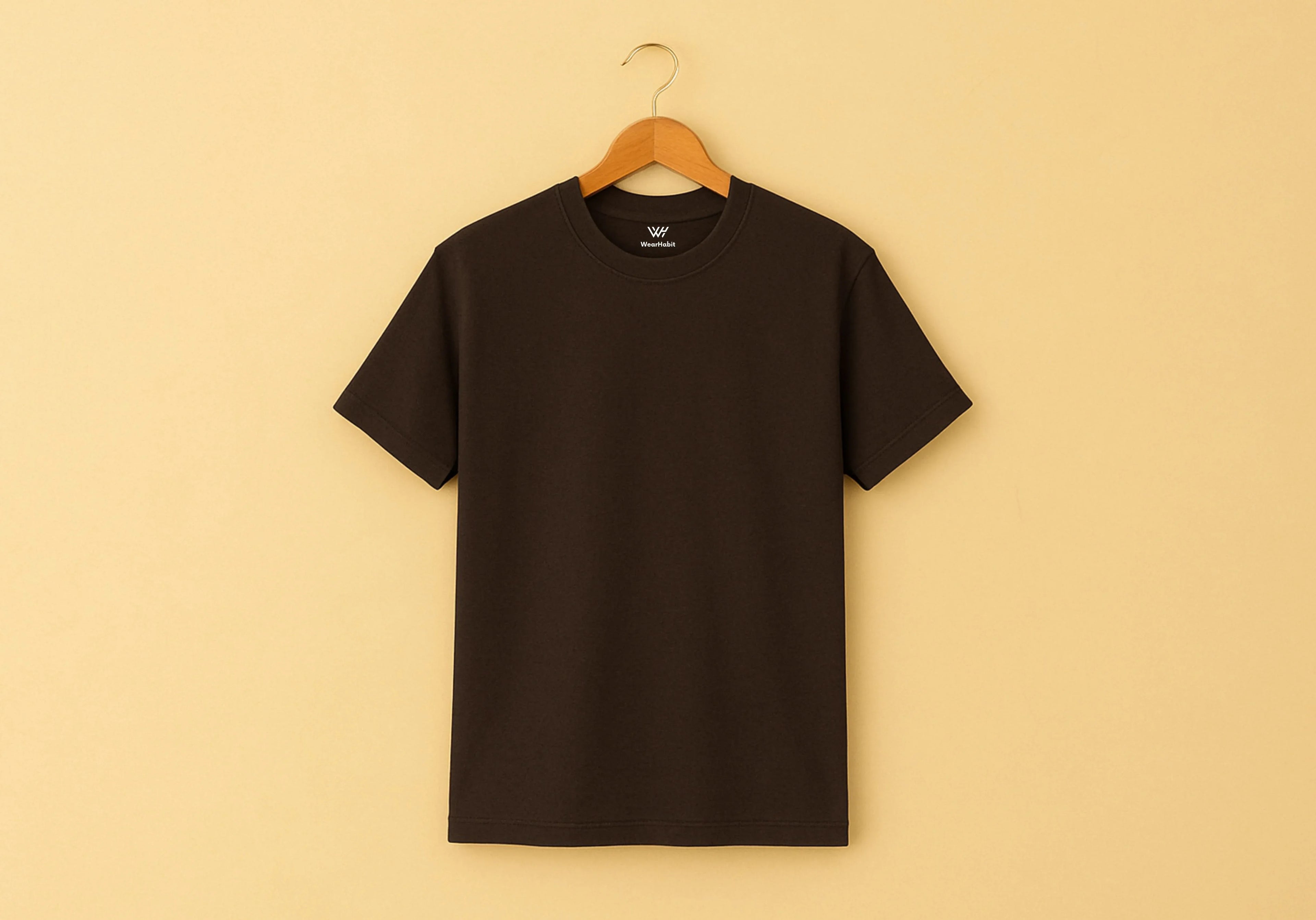 Black t-shirt on a wooden hanger against a beige background
