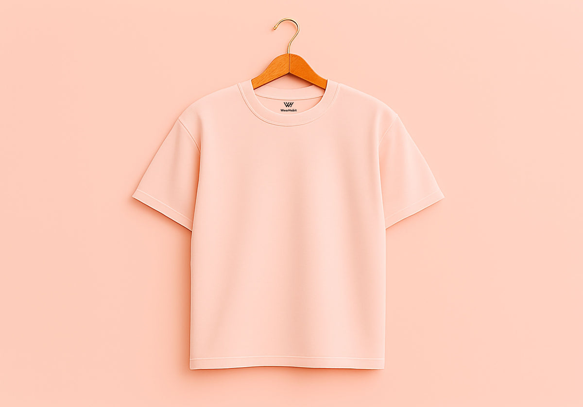 Pink t-shirt on a wooden hanger against a pink background