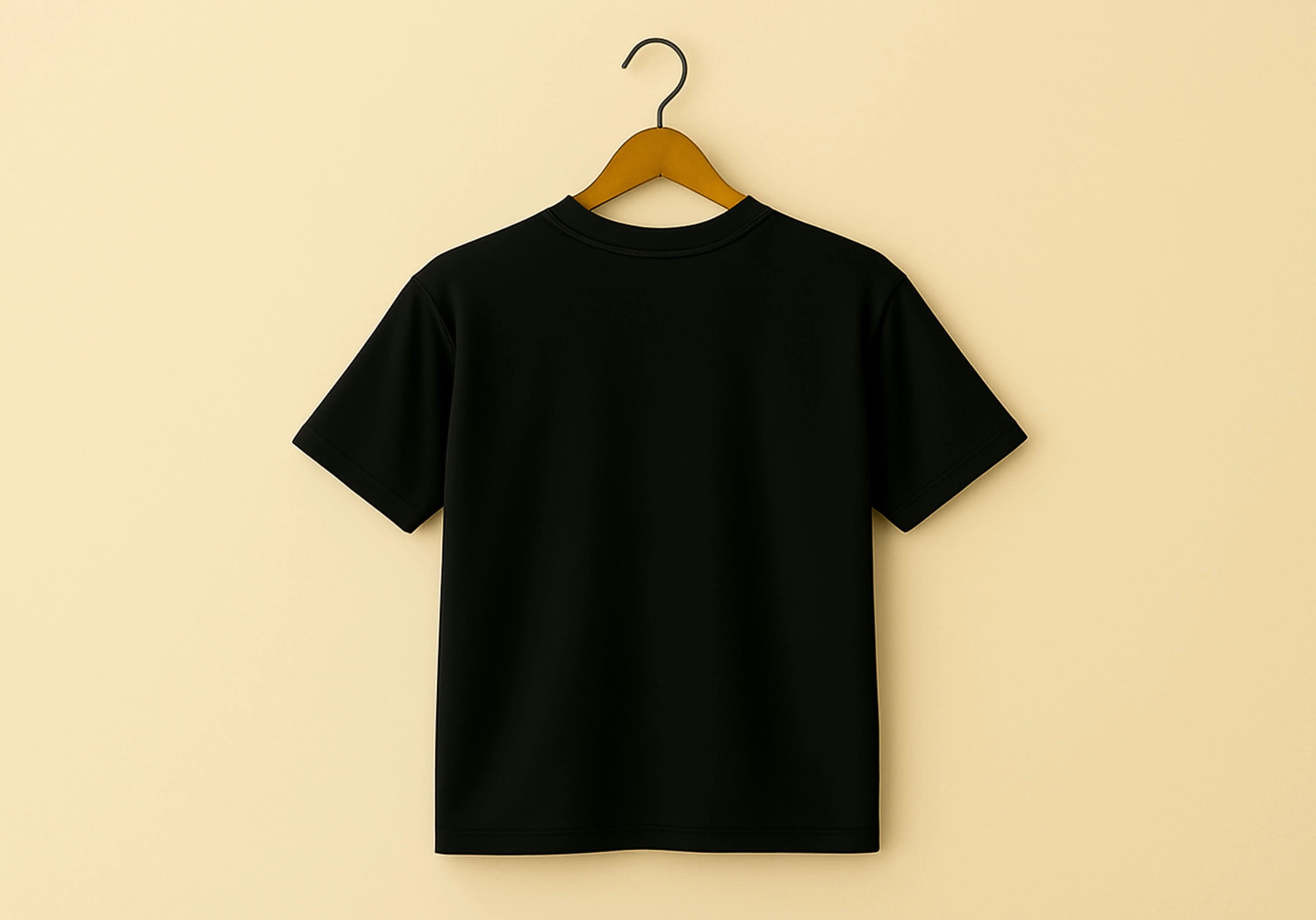 Black t-shirt on a wooden hanger against a beige background