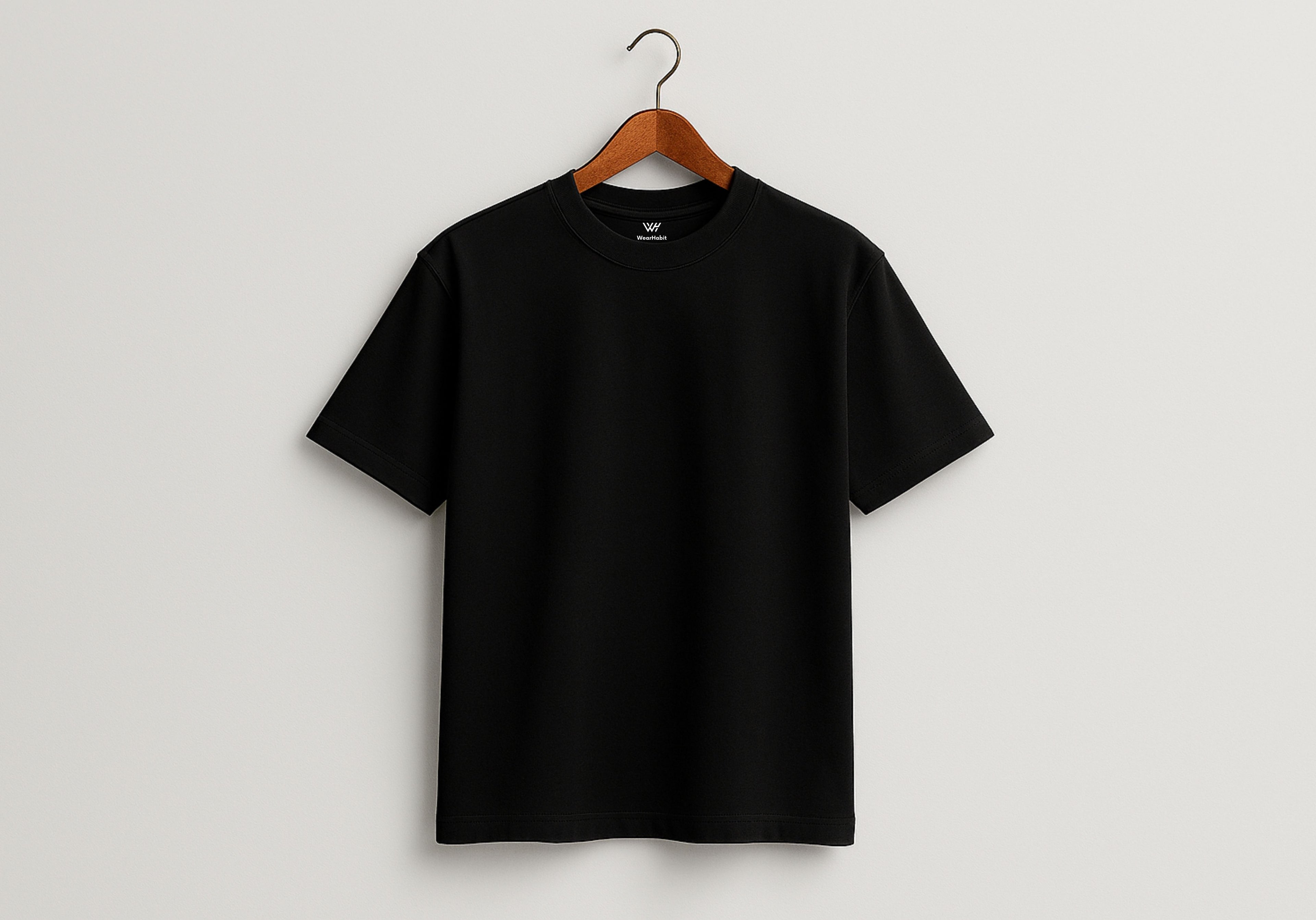 Black t-shirt on a wooden hanger against a light gray background