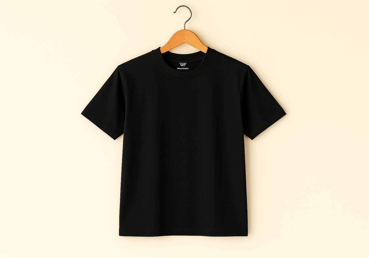 Black t-shirt on a wooden hanger against a beige background