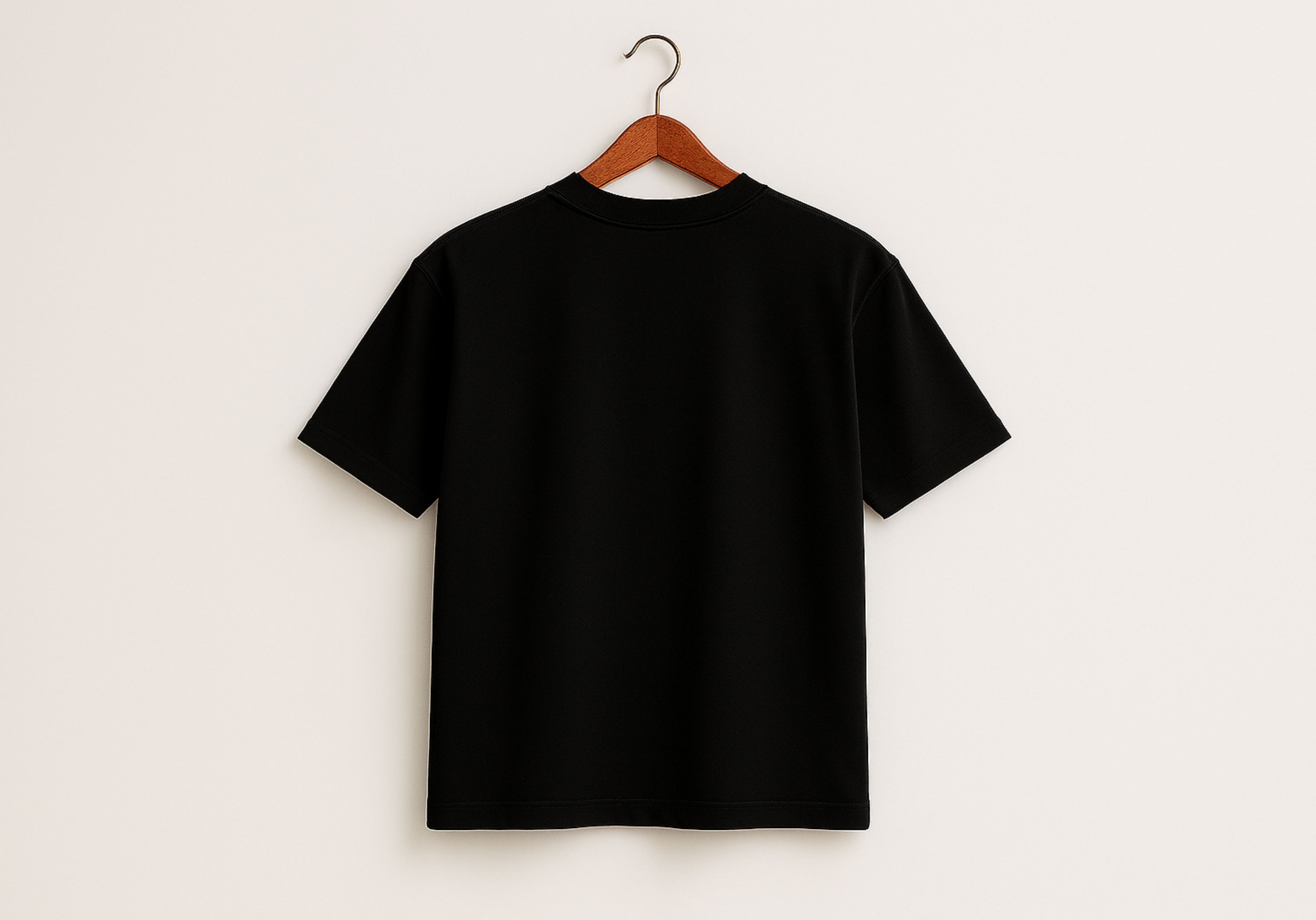 Black t-shirt on a wooden hanger against a white background