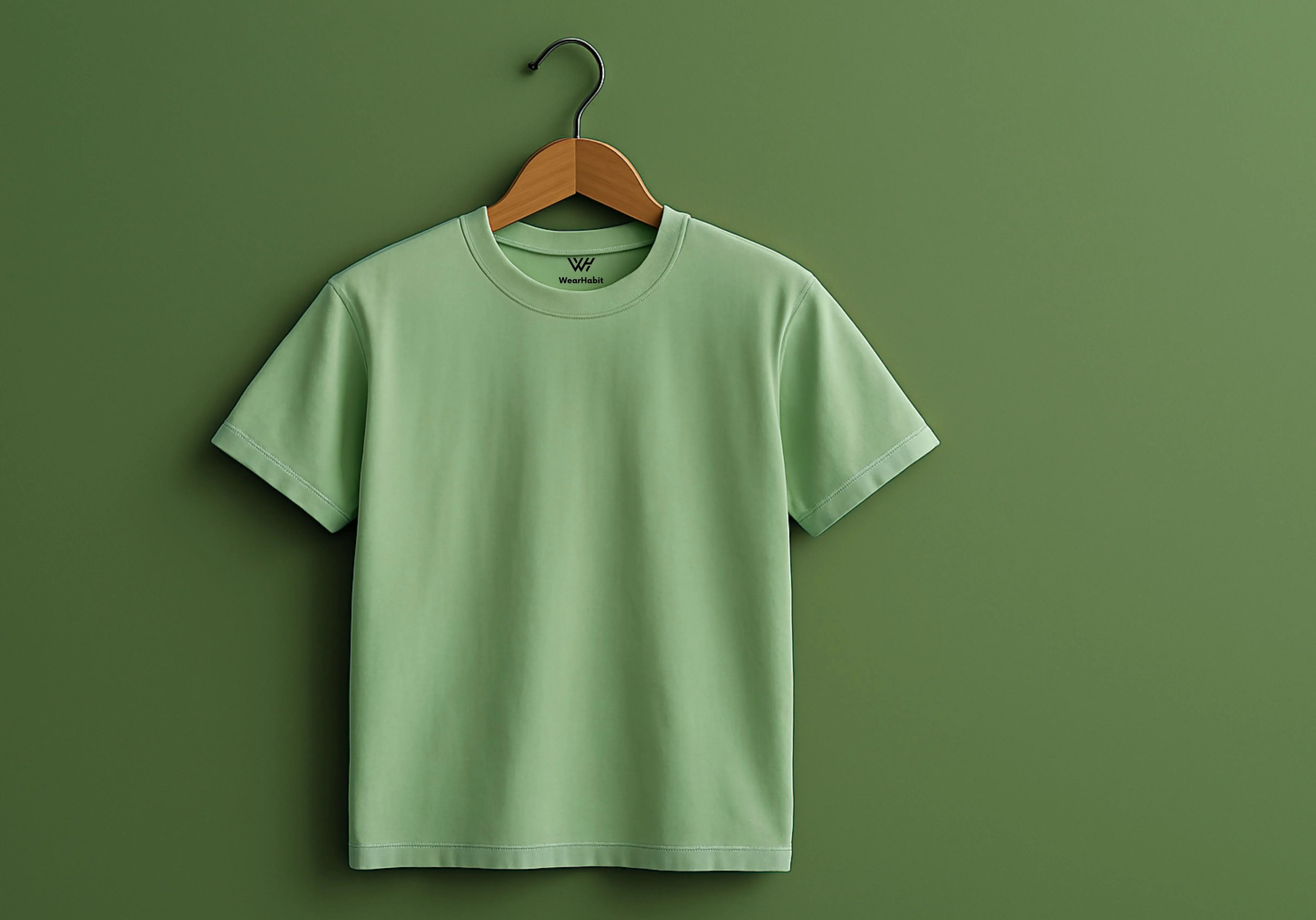 Green t-shirt on a wooden hanger against a green background
