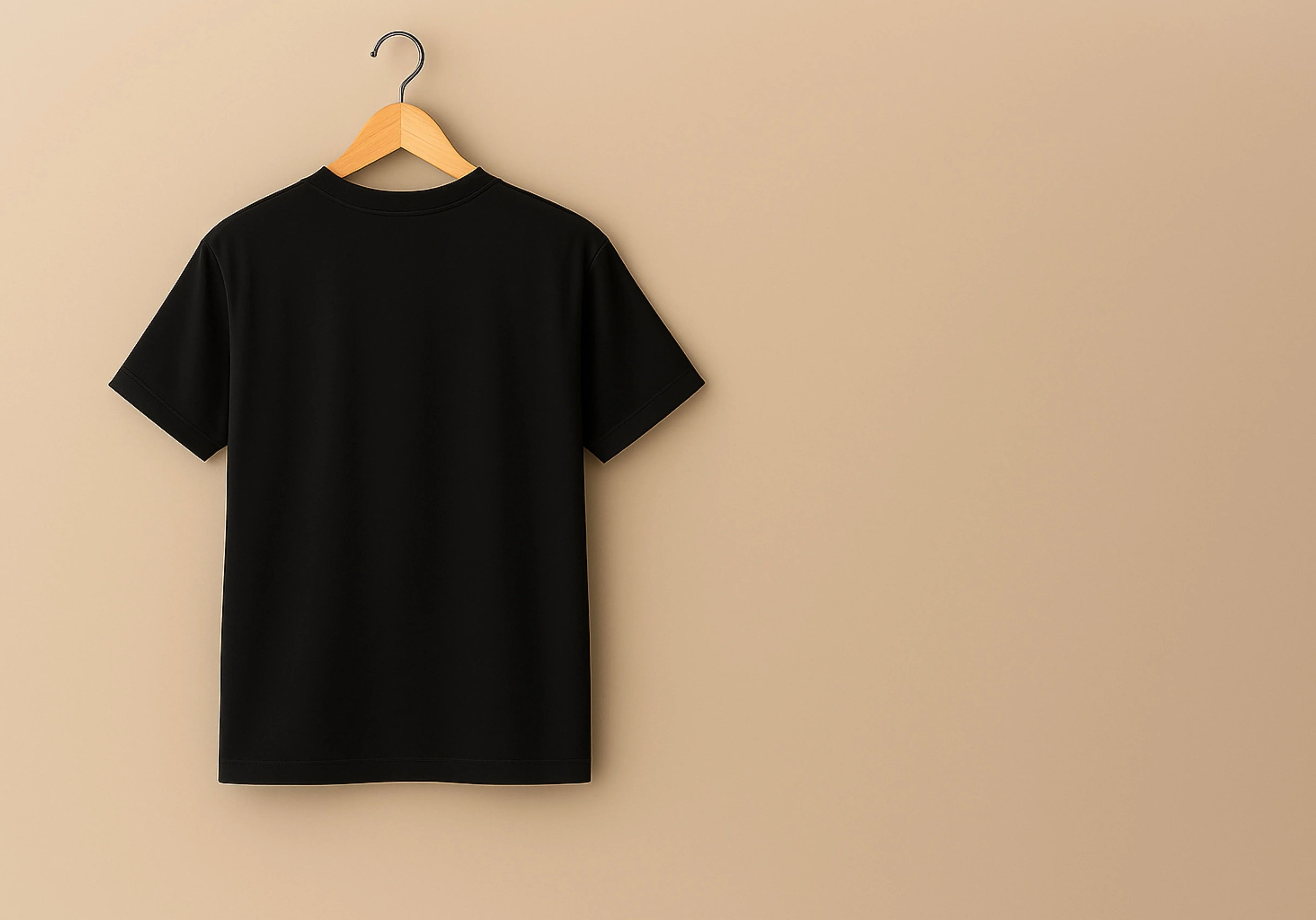 Black t-shirt on a wooden hanger against a beige background