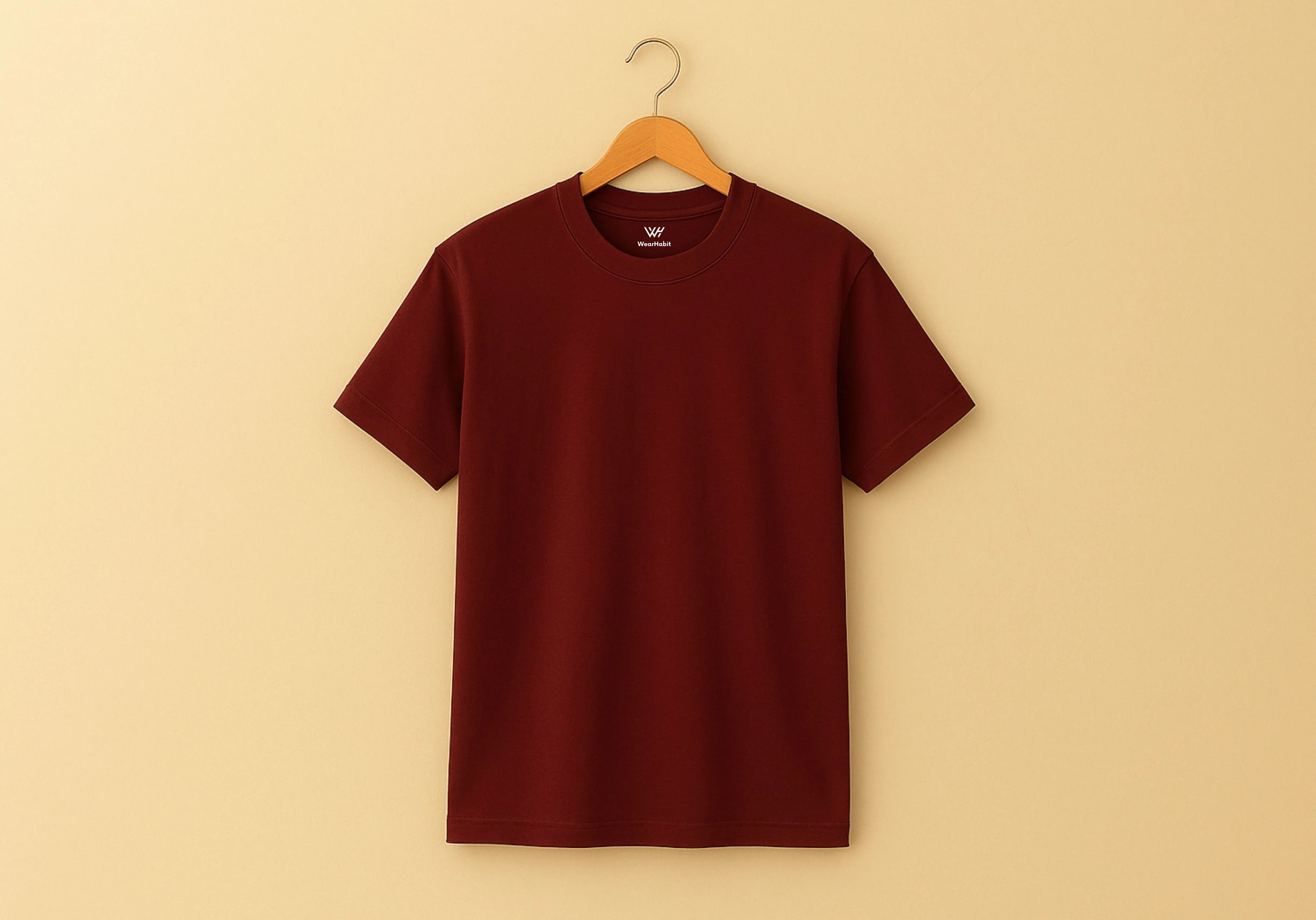 Maroon t-shirt on a wooden hanger against a beige background